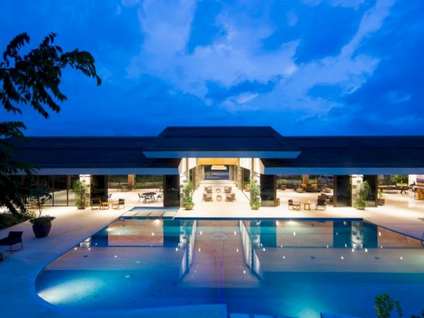 A luxurious pool area with modern architecture, surrounded by lounge chairs and lit up against a twilight sky, creating a serene ambiance.