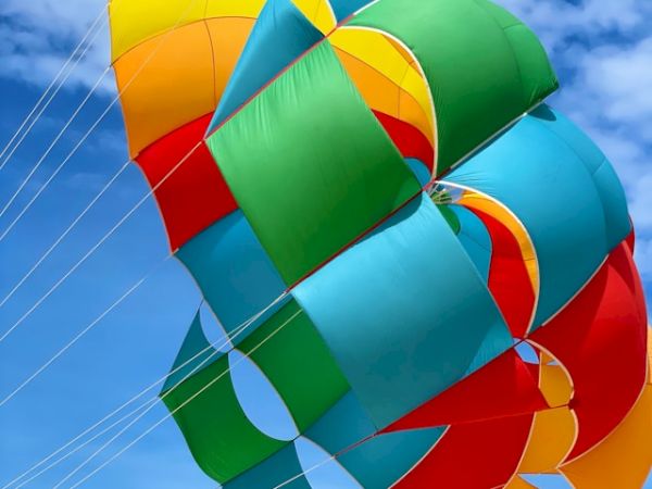 A colorful parachute canopy fills the sky against a bright blue backdrop, capturing a vibrant scene.