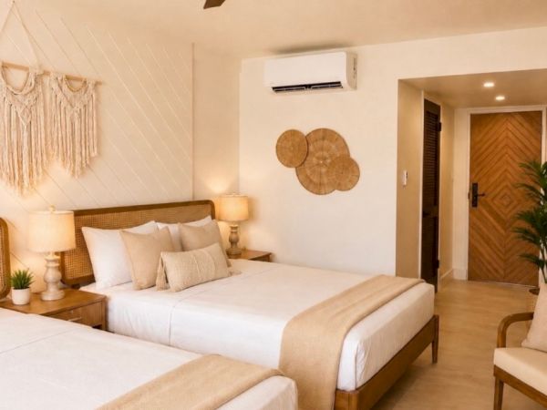 A bright modern bedroom with two beds, a ceiling fan, woven decor, and warm wood doors.